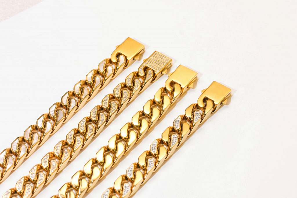 Close-up of gold chains with diamond inlays on white background, showcasing luxury and style.